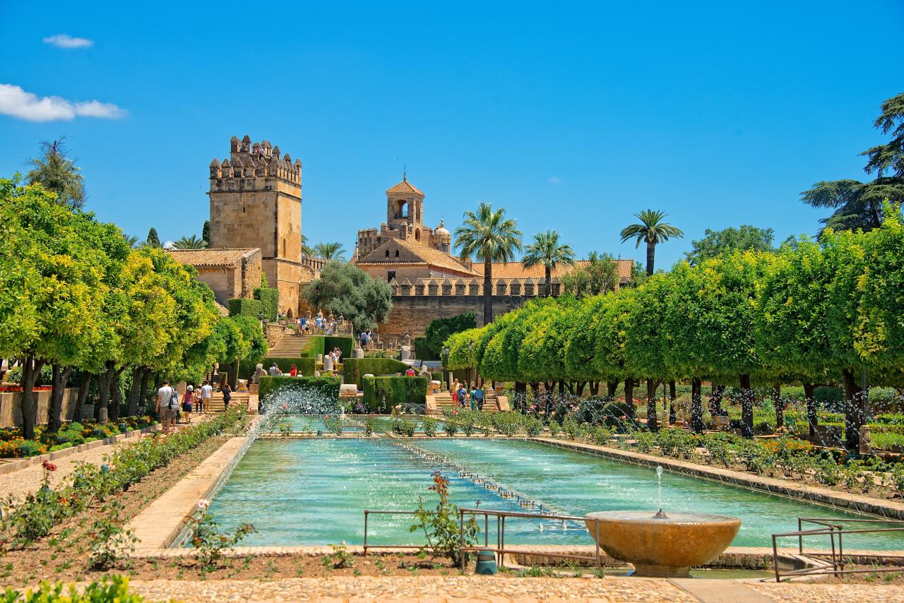 Alcázar von Cordoba mit Brunnen im Vordergrund vor blauem Himmel.