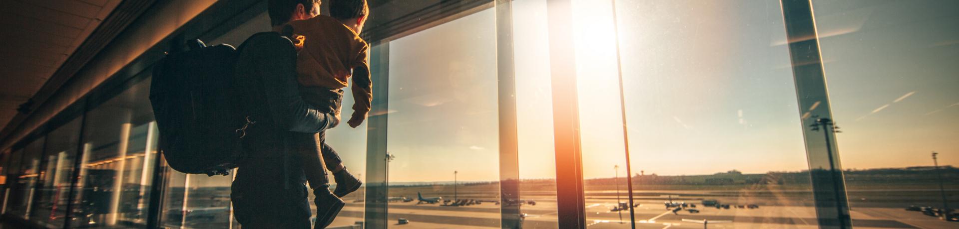 Vater mit Kind auf dem Arm in einem Flughafenterminal