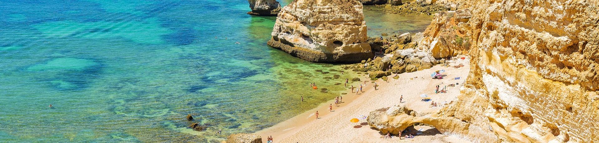 Praia da Marinha an der Algarve mit türkisfarbenem Wasser, Klippen und Menschen beim Sonnenbaden und Schwimmen.