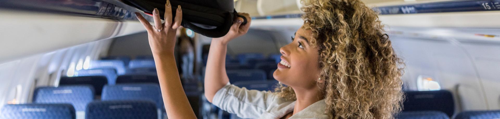 Frau mit Handgepäck im Flugzeug