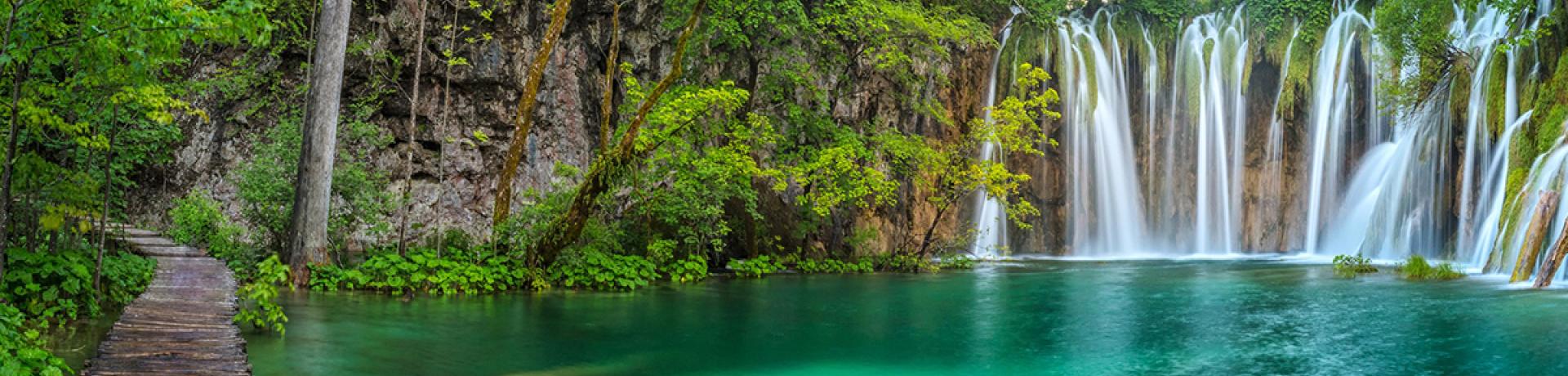 See mit Steg vor kleinem Wasserfall