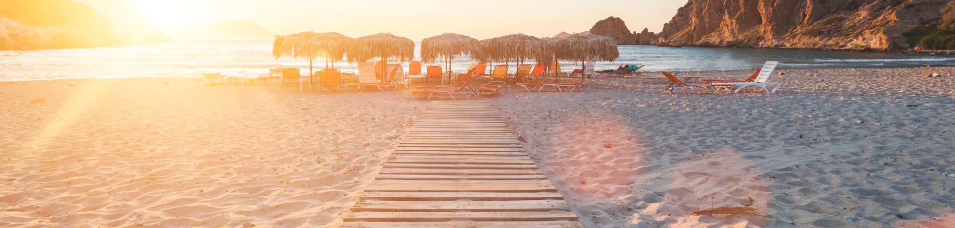 Strand mit Strandliegen bei Sonnenuntergang