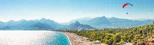 Panorama des Strandes von Paragliding in Antalya mit Bergen im Hintergrund.
