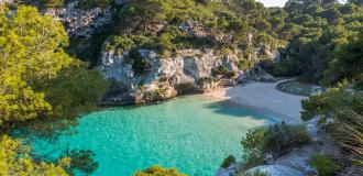 Blick auf die menschenleere Cala Macarelleta auf Menorca mit türkisfarbenem Wasser.