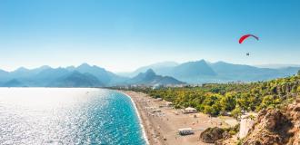 Panorama des Strandes von Paragliding in Antalya mit Bergen im Hintergrund.