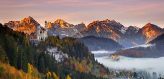 Schloss Neuschwanstein umgeben von Herbstlaub bei Sonnenaufgang.