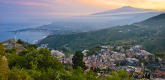 Blick auf Taormina am Abend mit Vulkan Ätna im Hintergrund.