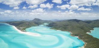 Küste der Whitsunday Islands in Queensland aus der Vogelperspektive mit azurblauem Wasser.