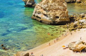 Praia da Marinha an der Algarve mit türkisfarbenem Wasser, Klippen und Menschen beim Sonnenbaden und Schwimmen.
