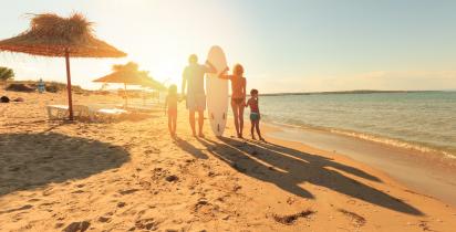 Familie mit Surfbrett am Strand