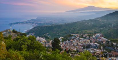 Blick auf Taormina am Abend mit Vulkan Ätna im Hintergrund.