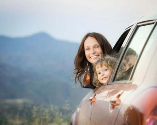Mutter und Kind im Auto vor Alpenpanorama
