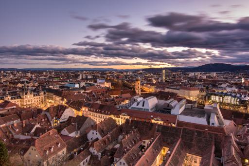 Blick über die Altstadt von Graz am Abend mit einem leicht bewölkten Himmel.