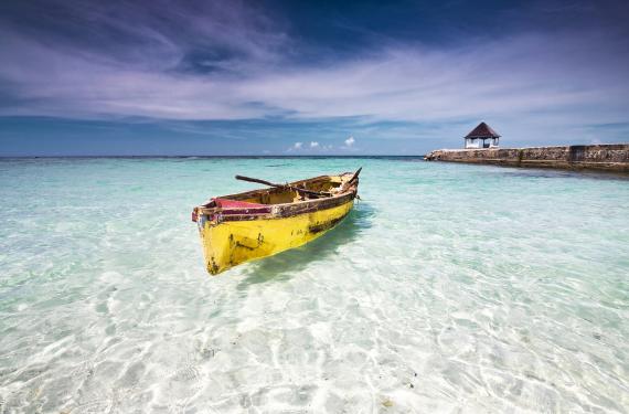 Fischer Kajak an der Nordküste Jamaikas in klarem Wasser mit Steg und Pavilion im Hintergrund.