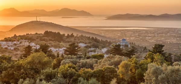 Hügellandschaft auf Kos bei Sonnenuntergang mit dem Meer im Hintergrund.