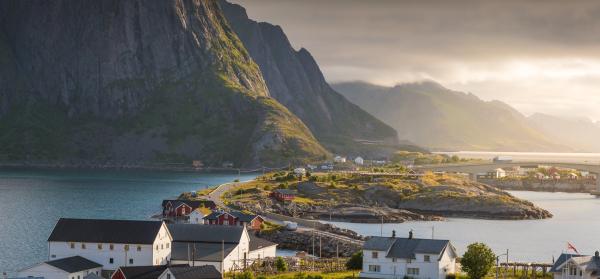 Küste und Berge auf Lofoten mit Häusern im Vordergrund.