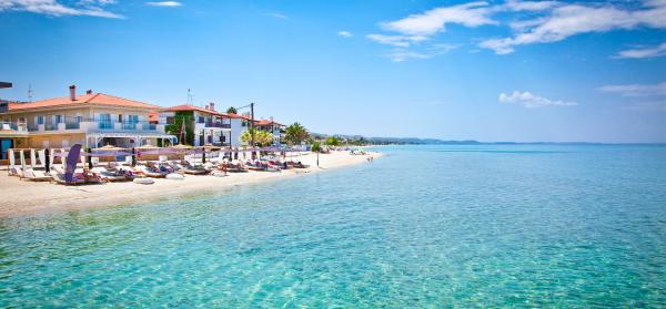 Pefkochori Meer und Strand von Pefkochori auf Chalkidiki mit Häusern im Hintergrund.
