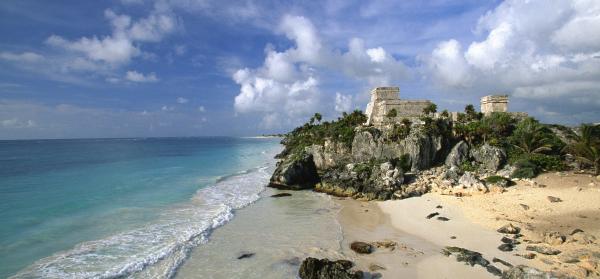 Seitlicher Blick auf den Playa Ruinas in Tulum mit Mayaruinen und Meer.
