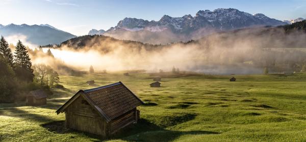 Geroldsee im Allgäu mit Morgennebel und Bergen im Hintergrund.