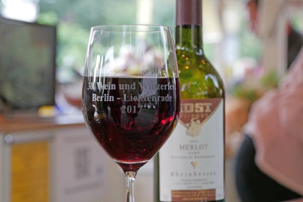 Gefülltes Rotweinglas mit Weinflasche im Hintergrund