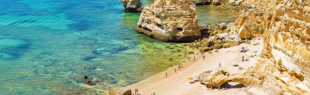 Praia da Marinha an der Algarve mit türkisfarbenem Wasser, Klippen und Menschen beim Sonnenbaden und Schwimmen.