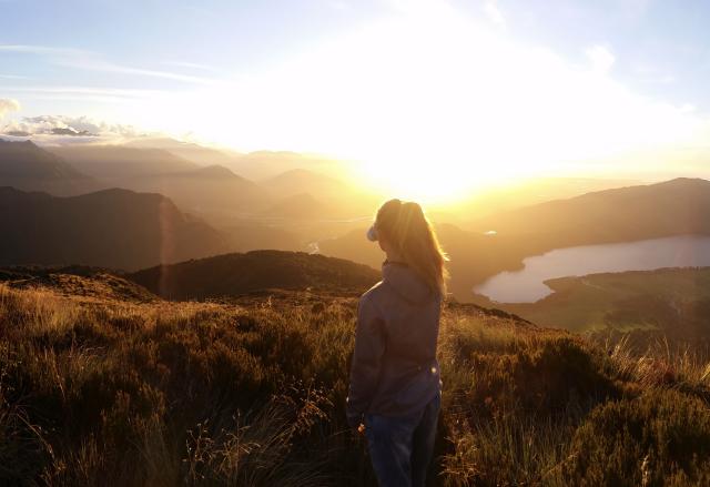 Frau auf Berg im Sonnenuntergang