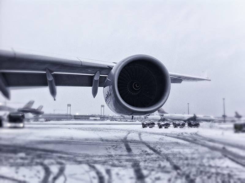 Flugzeugflügel mit Turbine und Schnee auf dem Rollfeld