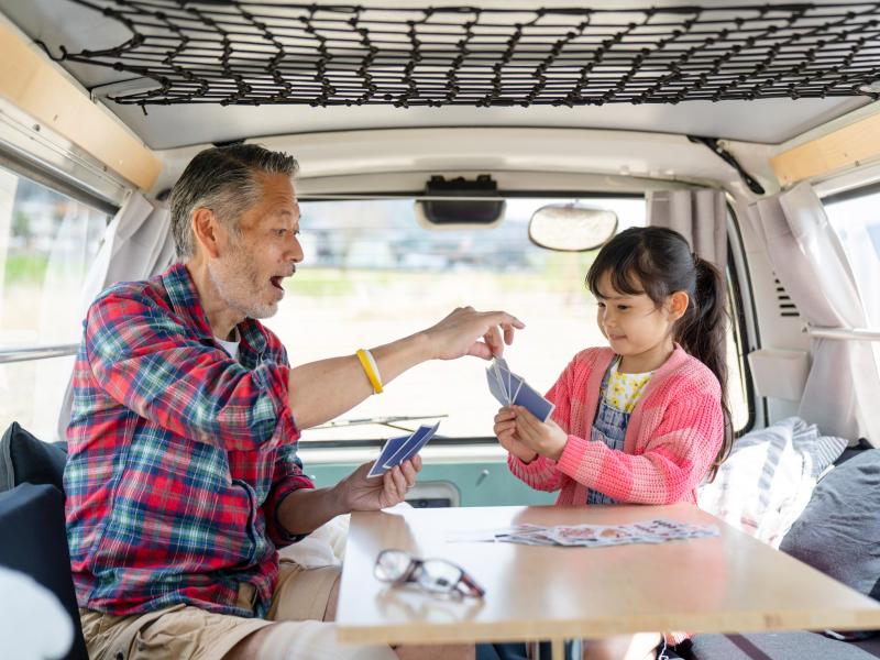 Kind und Großvater beim Kartenspiel im Camper