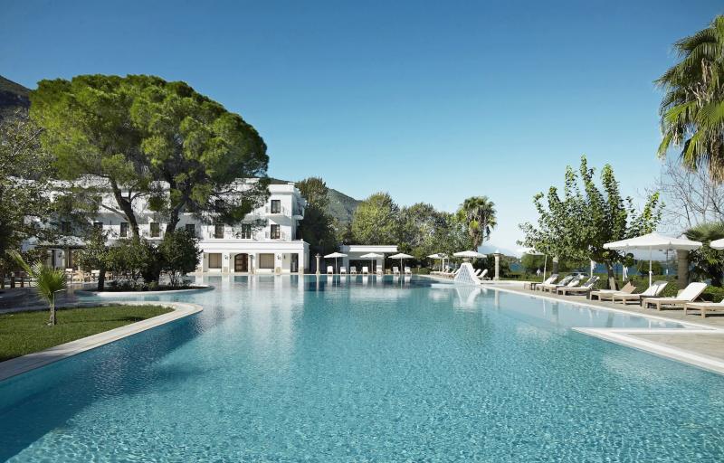 Thermalpool des Mitsis Galini Wellness Resorts mit Blick auf das klassische Kurhotel und grüne Berglandschaft