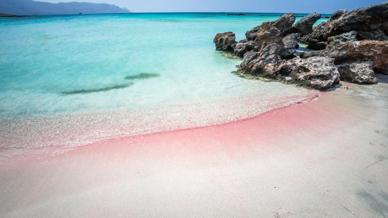 Weiß-roter Sandstrand mit türkisem Wasser und Felsen
