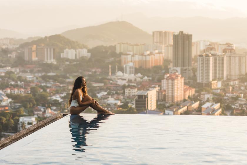 Frau am Pool mit Stadtblick