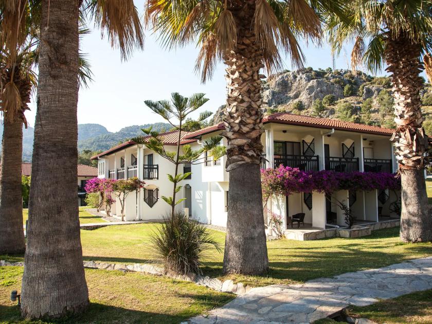 Gepflegte Hotelanlage mit Palmen und Bougainvillea im Tui Blue Sarigerme Park vor grüner Bergkulisse in der Türkei