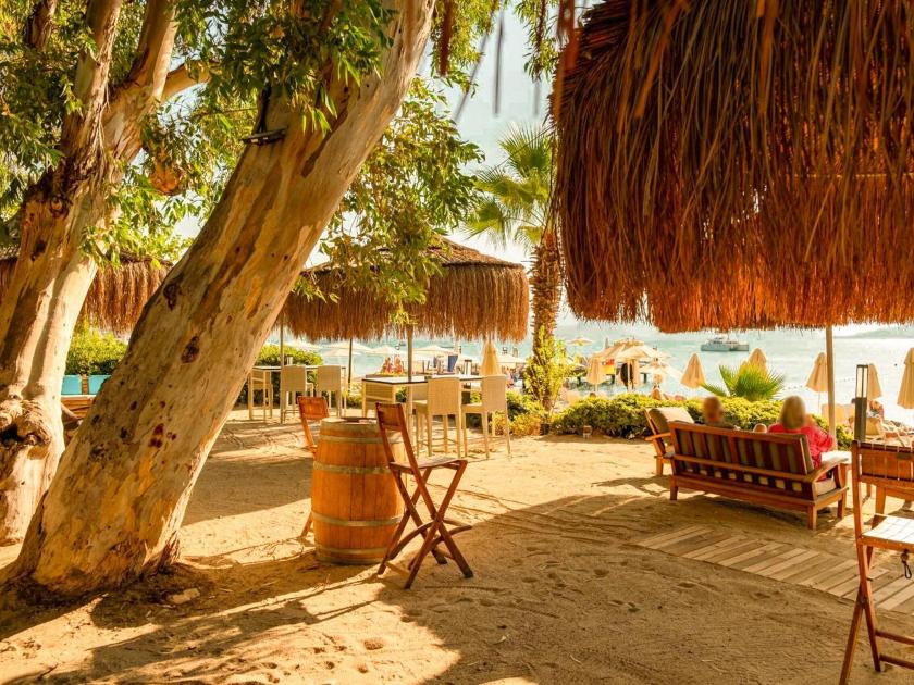 Gemütlicher Strandbereich mit Liegen und Strohdächern im Tui Blue Grand Azur am Meer bei Sonnenschein