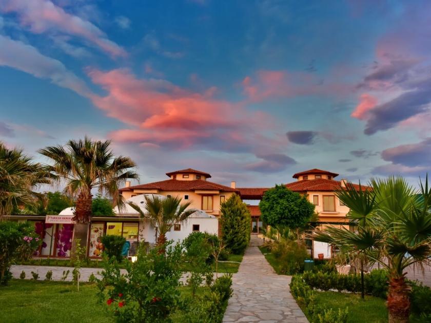 Hotelanlage mit Garten und Palmen im Tui Blue Angora Beach bei Sonnenuntergang unter farbenprächtigem Himmel