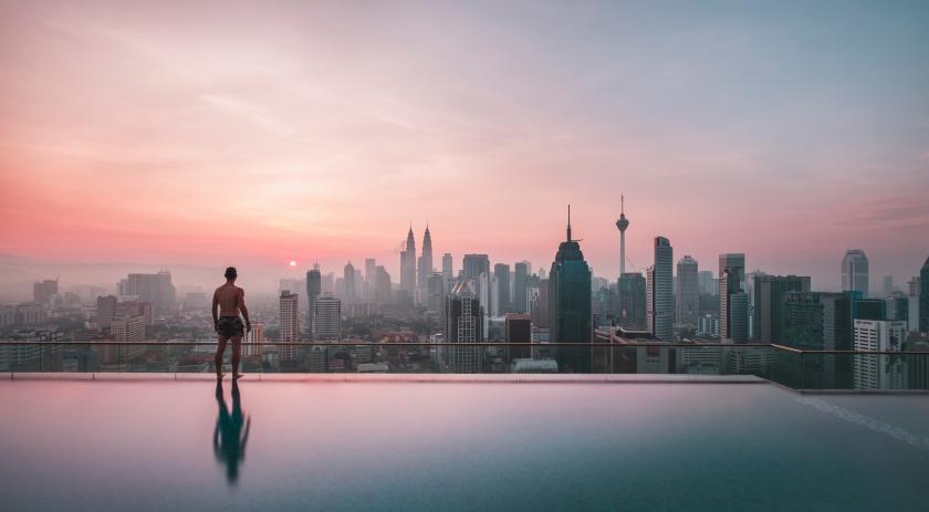 Mann blickt vom Pool auf Skyline