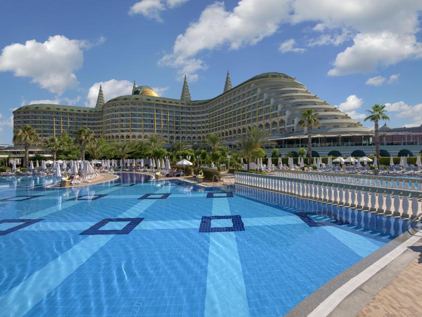 Luxuriöses 5-Sterne-Hotel mit außergewöhnlicher Architektur, großem Poolbereich und Palmen unter blauem Himmel.