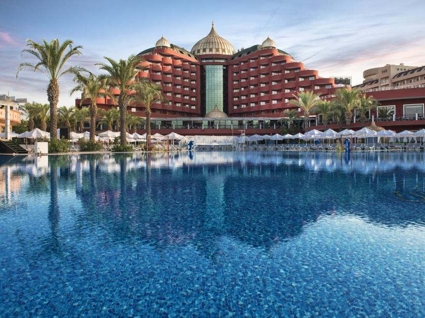 Luxuriöses 5-Sterne-Resort mit großer Poollandschaft, Palmen und orientalisch inspirierter Architektur in der Abenddämmerung.