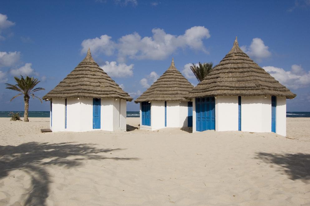 Djerba Weiße Hütten an einem Strand auf Djerba mit dem Meer im Hintergrund.