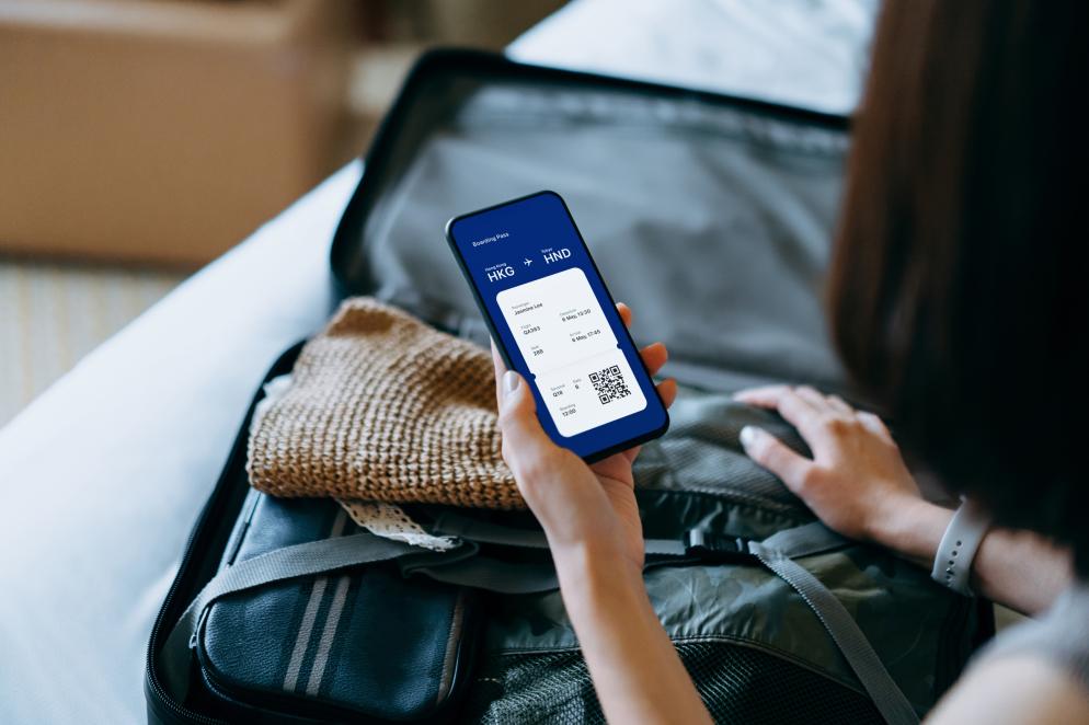 Boardkarte im Smartphone vor gepacktem Koffer Boardkarte im Smartphone vor gepacktem Koffer