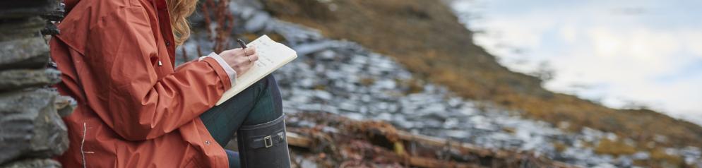 Ein Reisetagebuch hilft euch dabei, Gedanken und Gefühle zu ordnen. Frau schreibt Tagebuch