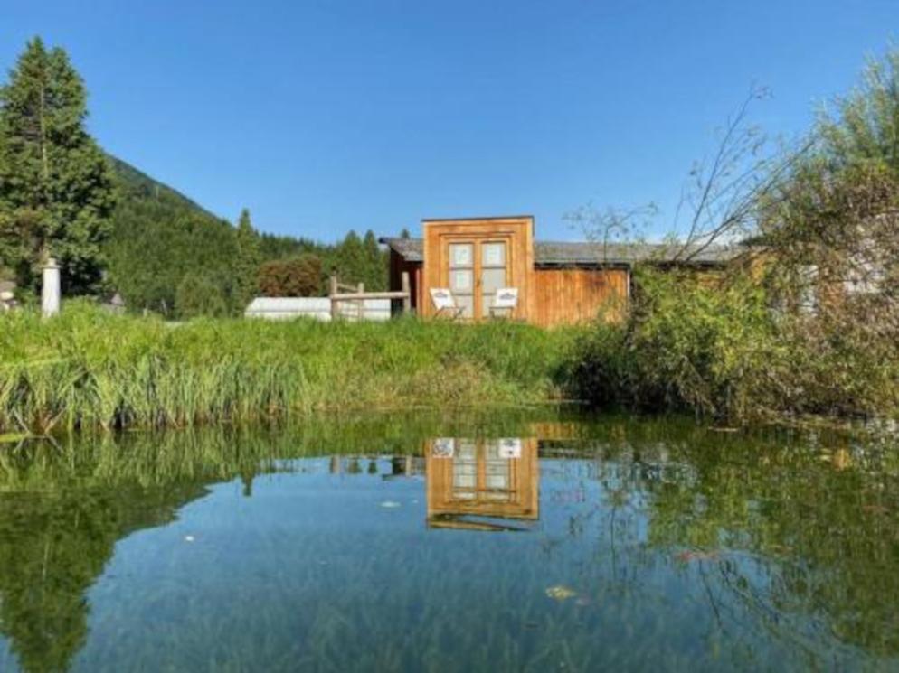 Quadratisches Tiny House vor Teich Quadratisches Tiny House vor Teich