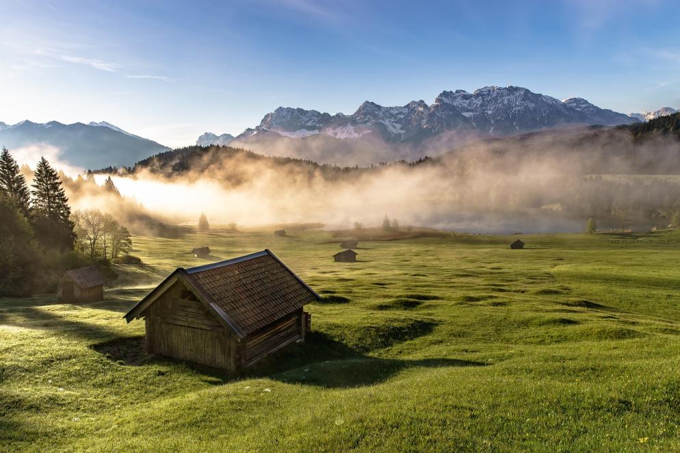 Geroldsee im Allgäu mit Morgennebel und Bergen im Hintergrund.