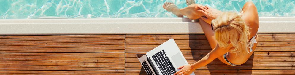 Frau mit Laptop am Pool
