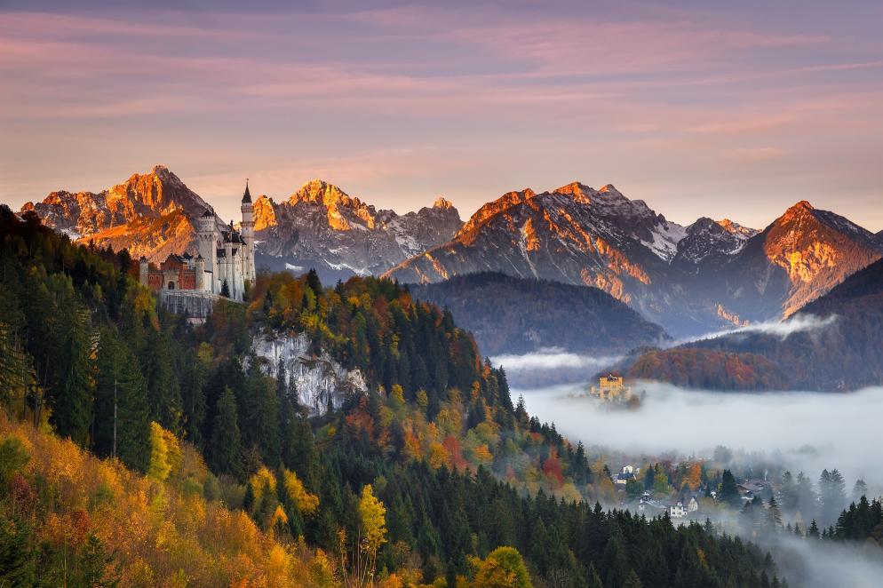 Schloss Neuschwanstein umgeben von Herbstlaub bei Sonnenaufgang.