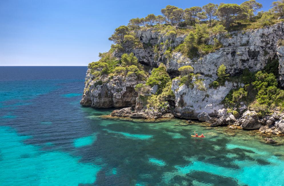 Cala Macarelleta - Menorca Cala Macarelleta auf Menorca mit Kajakfahrern im Hintergrund.